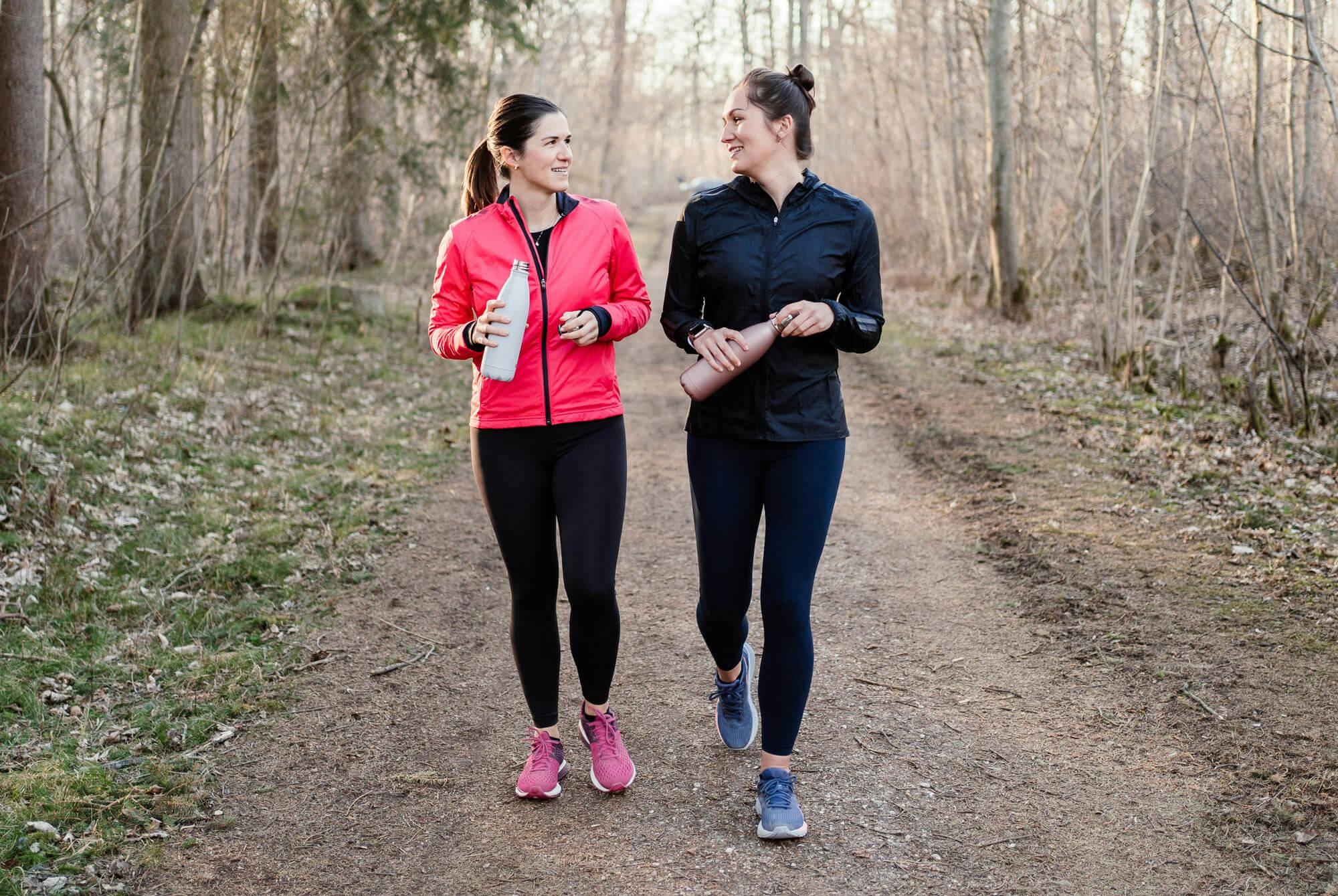 To kvinner går ved siden av hverandre i skogen