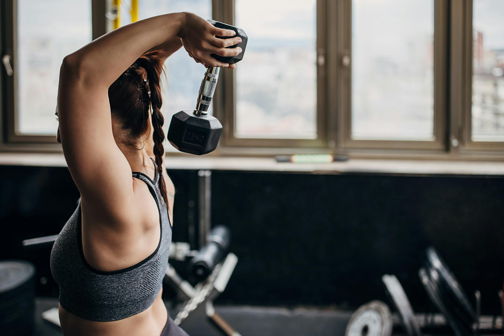 Kvinde udfører overhead extensions med dumbbell