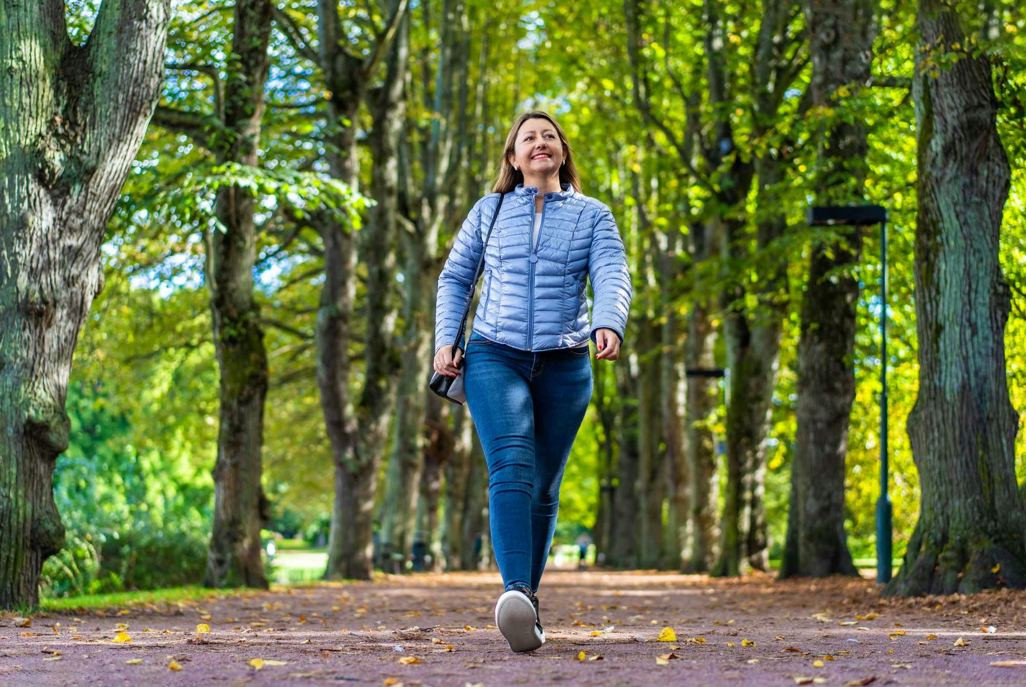 Smilende kvinne går tur i en park