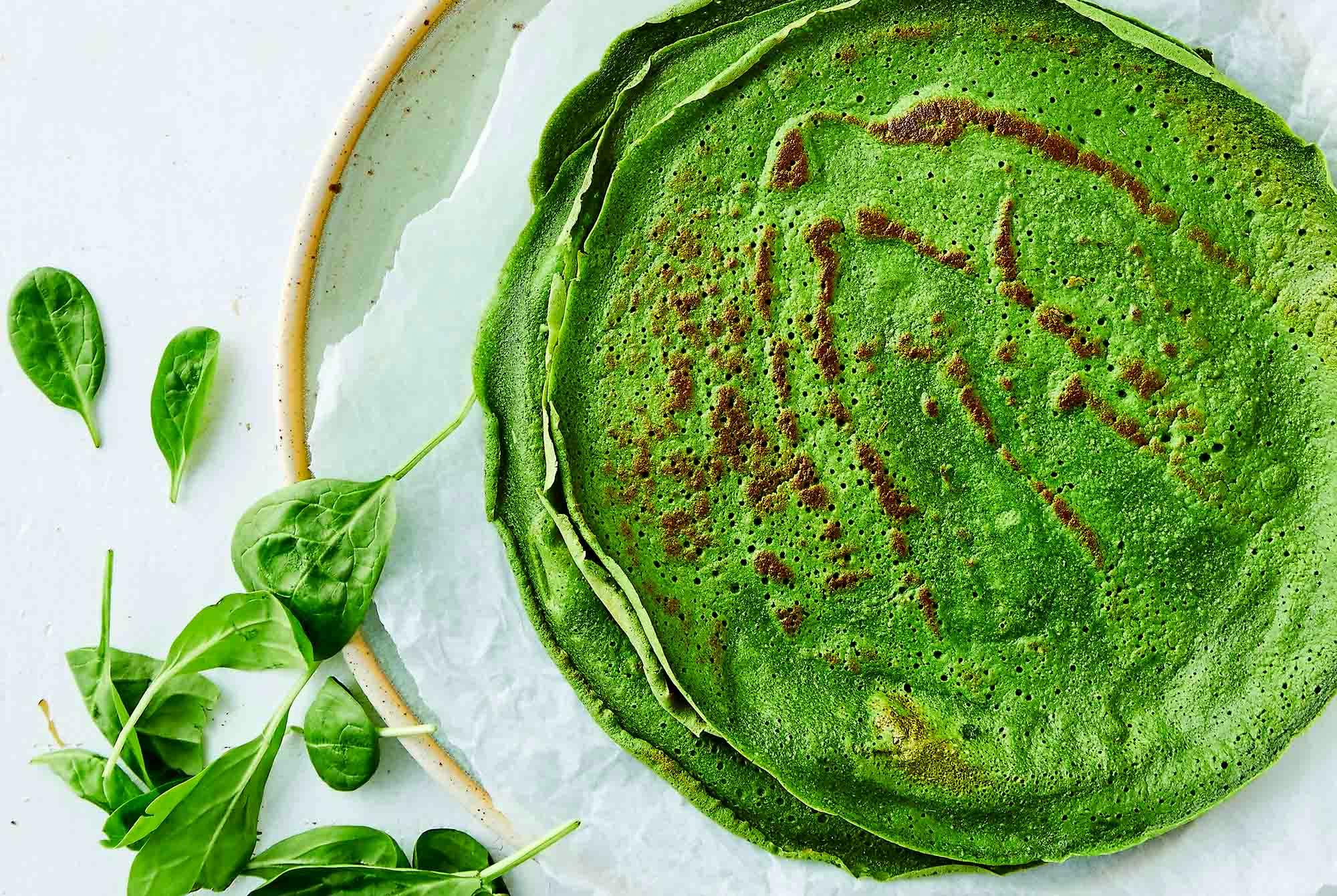 Tallrik med gröna pannkakor med spenat
