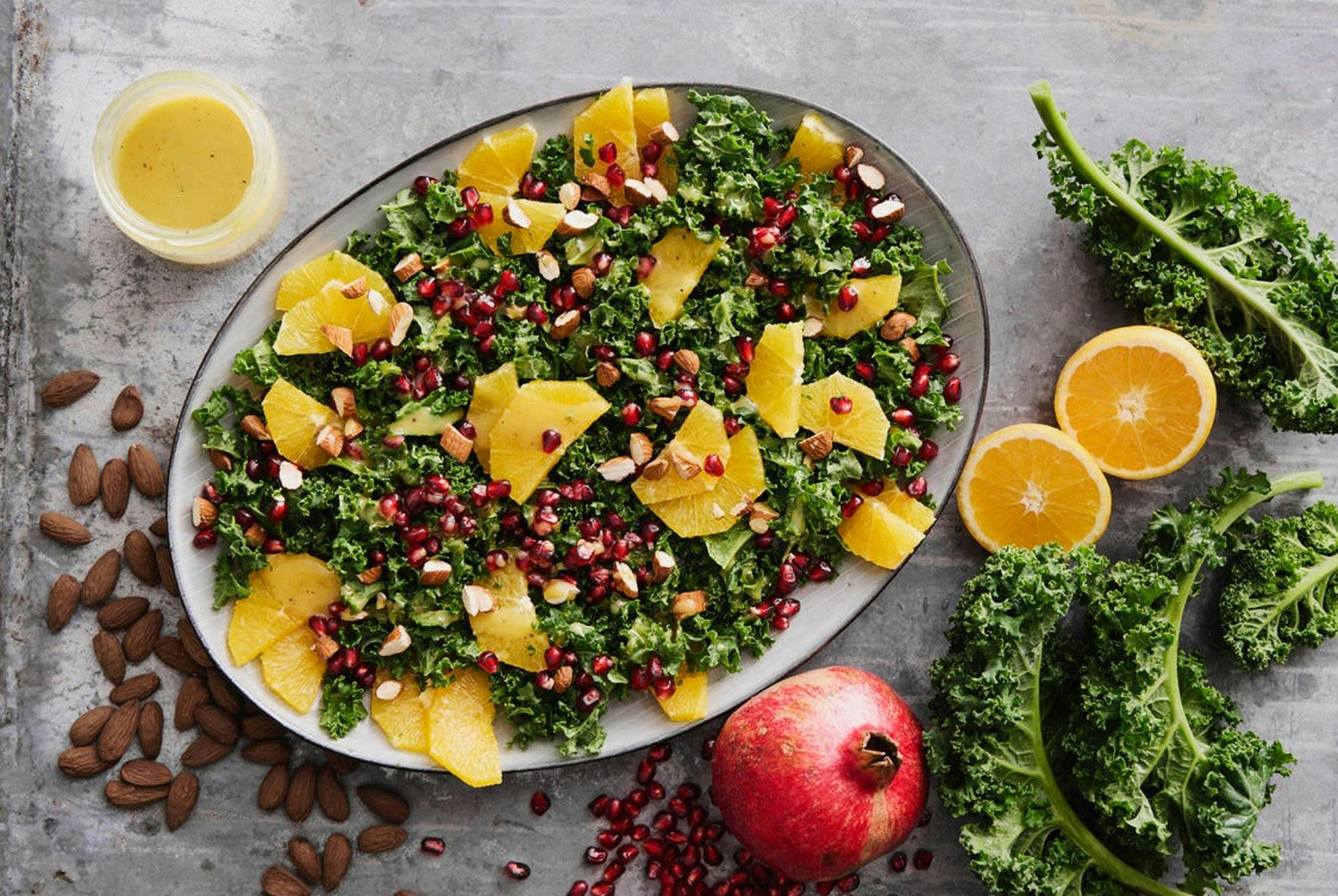 Ett fat med grönkålssallad med apelsin, granatäpple, mandlar och senapsdressing
