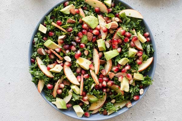 Skål med grønkålssalat med æbler, granatæblekerner og avocado.