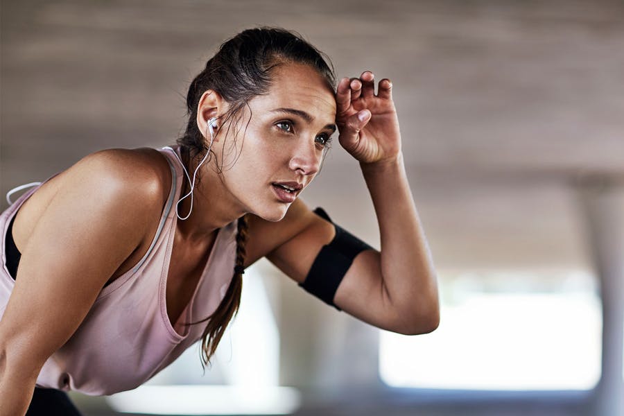 Kvinne svetter og puster ut etter en hard treningsøkt