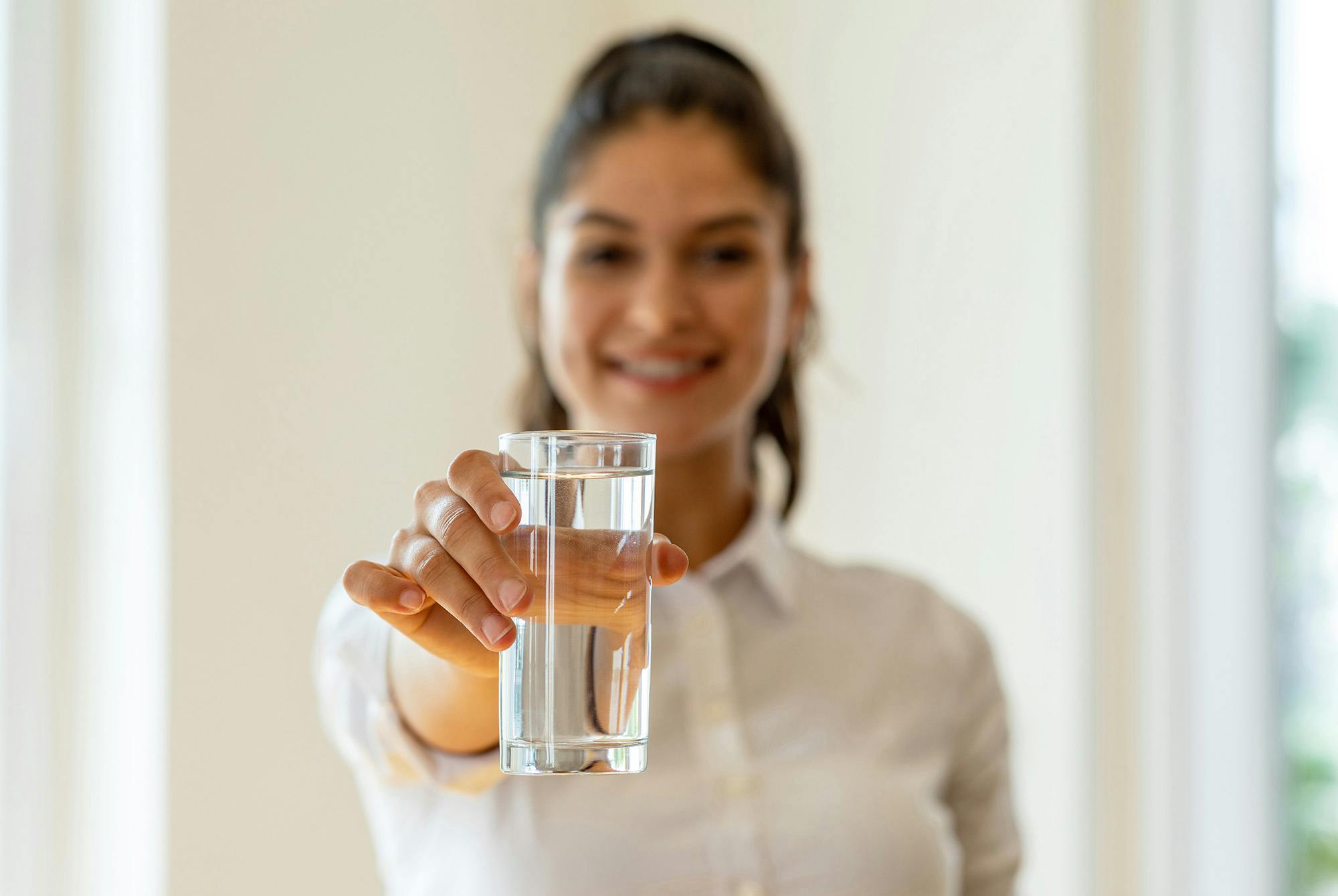 En kvinde med et glas vand for at stoppe hikke. Men hvorfor får man hikke?
