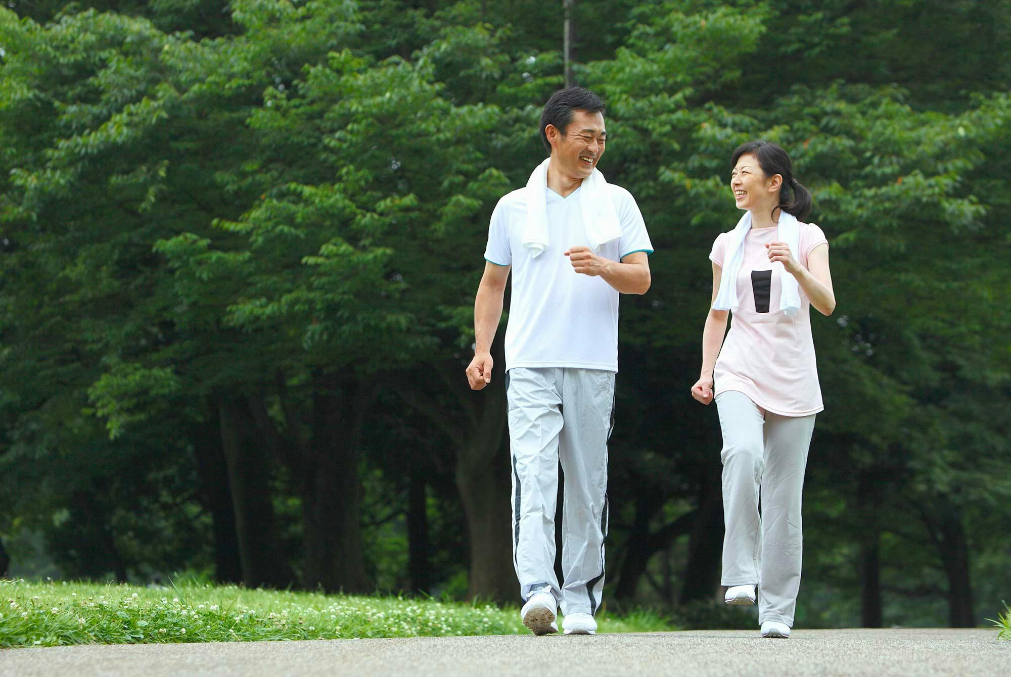 Japanilainen mies ja nainen kävelylenkillä puistossa.