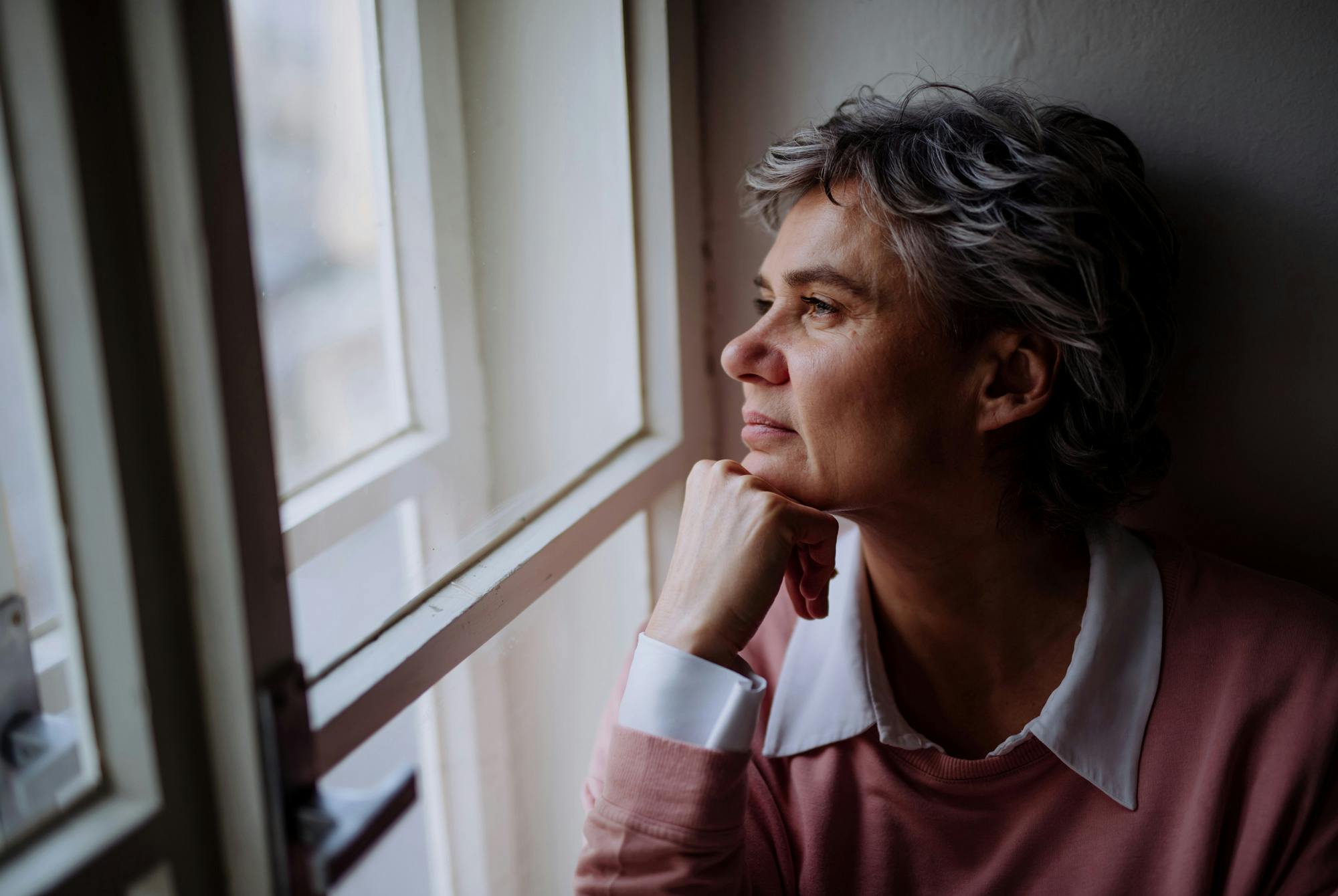 Moden kvinne ser ut av vinduet, vinterdepresjon