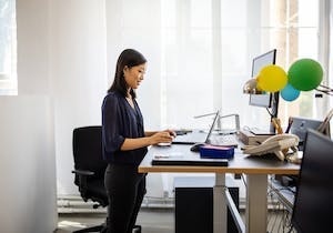 Kvinne står ved heve-senkebord på jobben