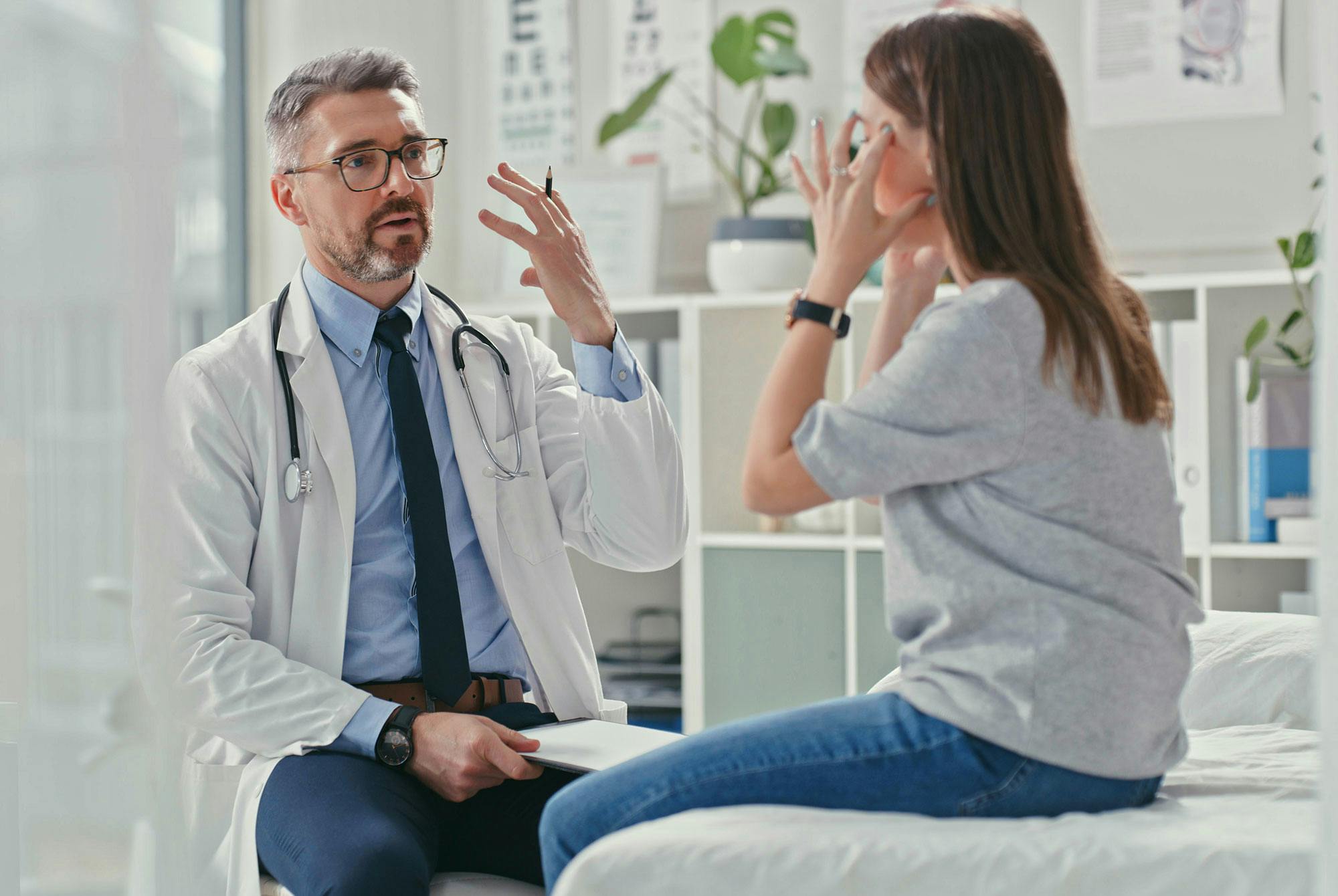 En kvinnlig patient förklarar smärtan hon upplever för sin läkare.