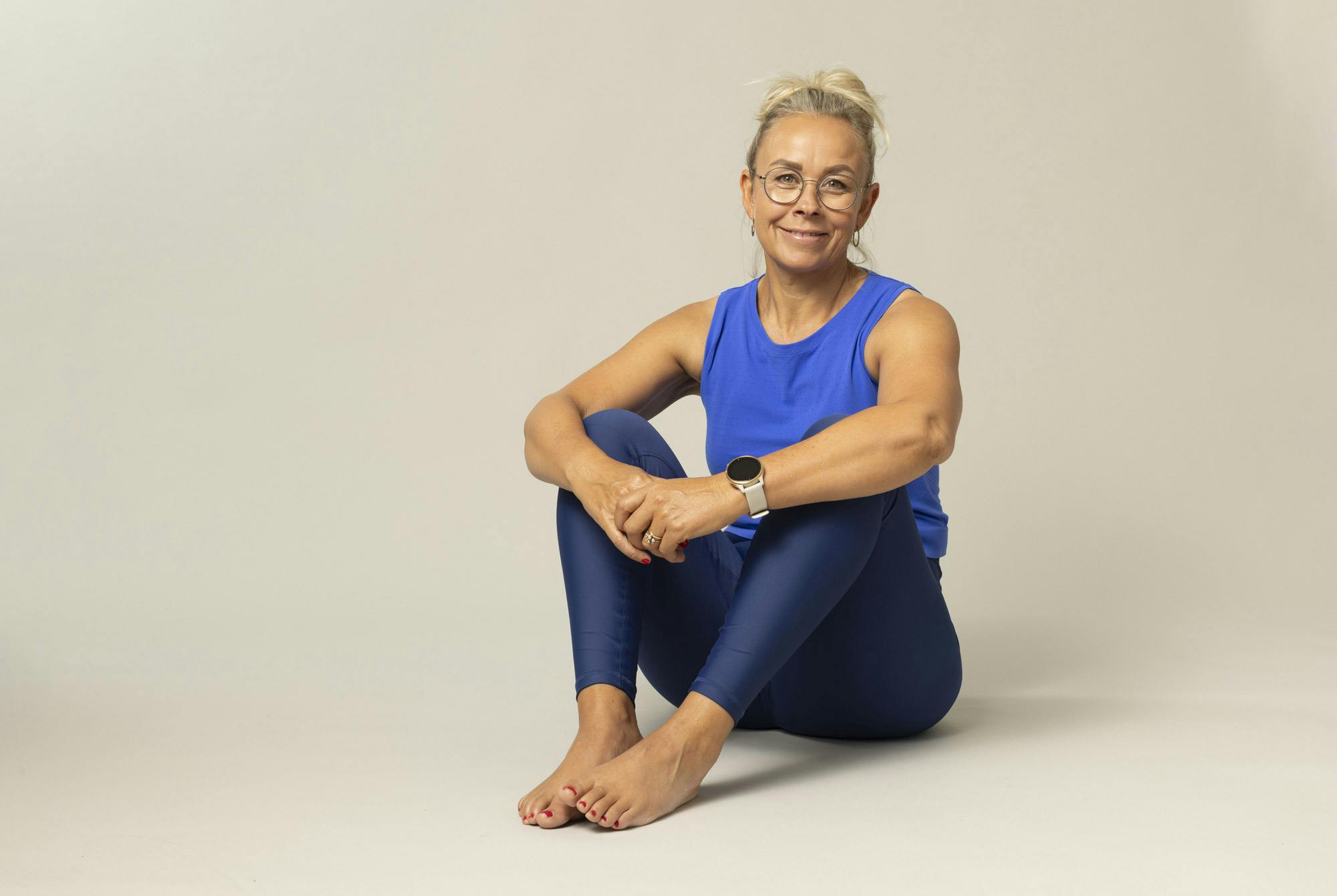 Smilende kvinne sitter på gulvet