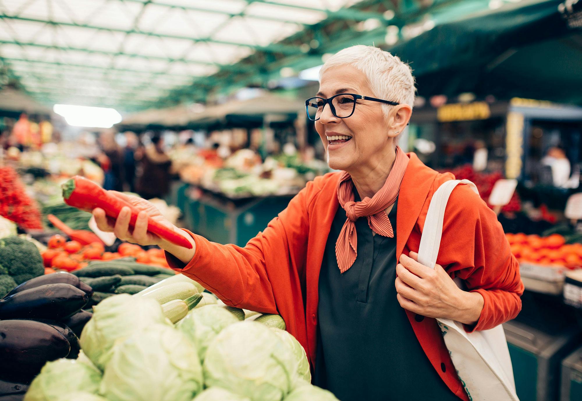 Kvinde køber grøntsager på et marked. Hun snakker flere sprog.