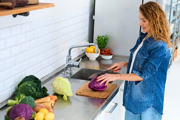 kvinde snitter grove grøntsager ved køkkenbord