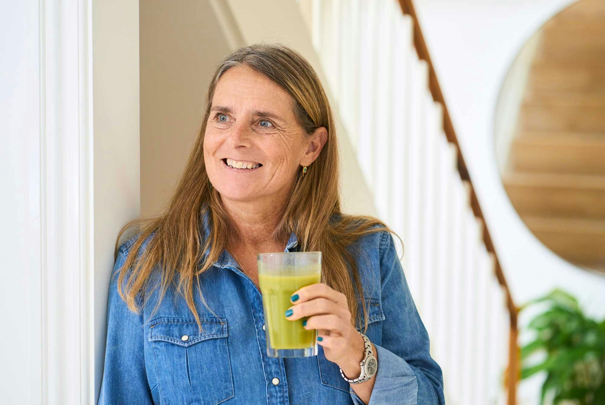 Kvinna dricker en grön smoothie med grönsaker.