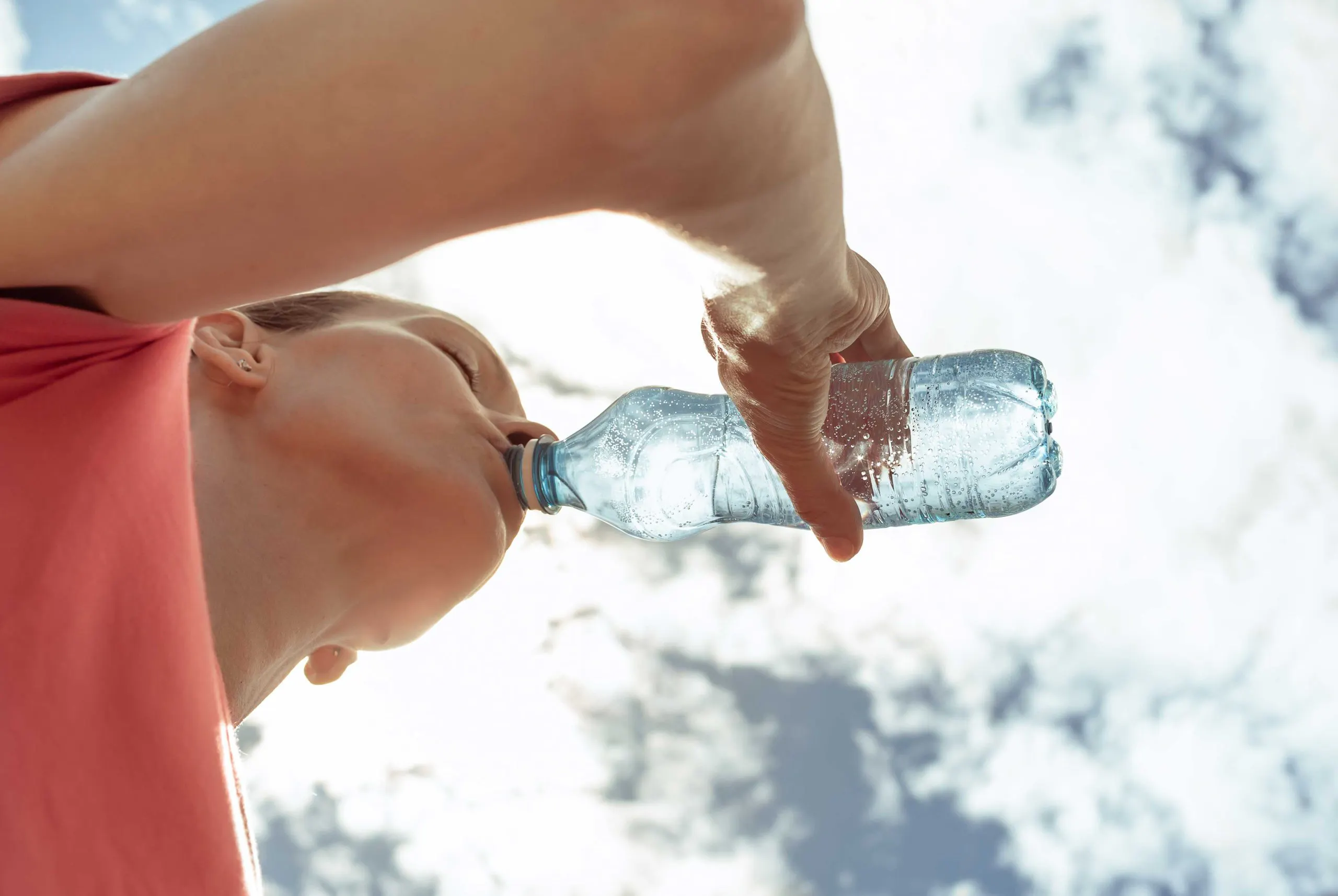 Kvinne drikker fra plastflaske.