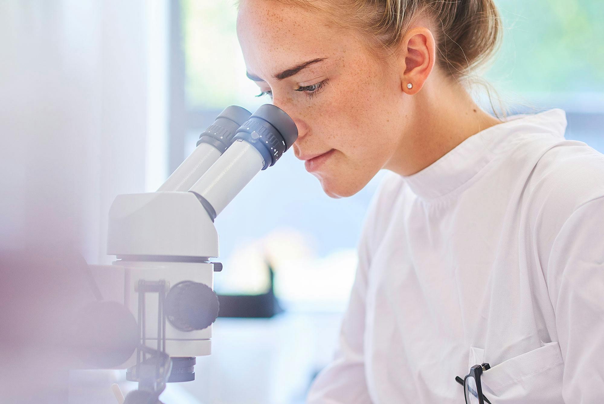 Læge kigger i mikroskop for at slå diagnose om urinsyregigt fast.