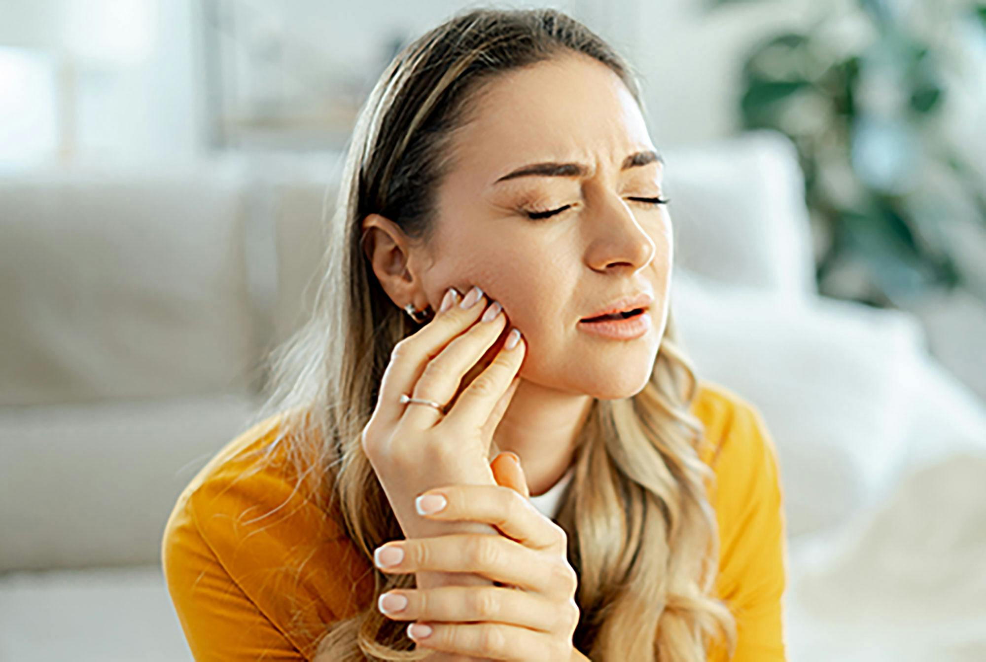 Kvinde tager sig til munden. Hun har ondt i tænderne og risikerer sygdom.