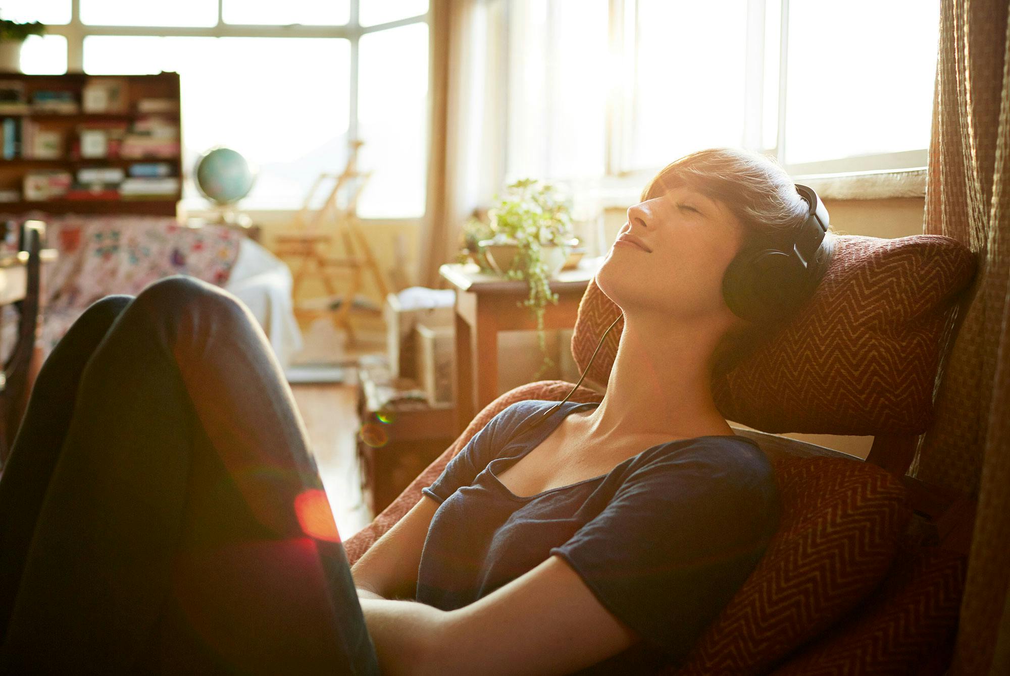 Kvinde lytter til musik i øretelefoner i sin stue.