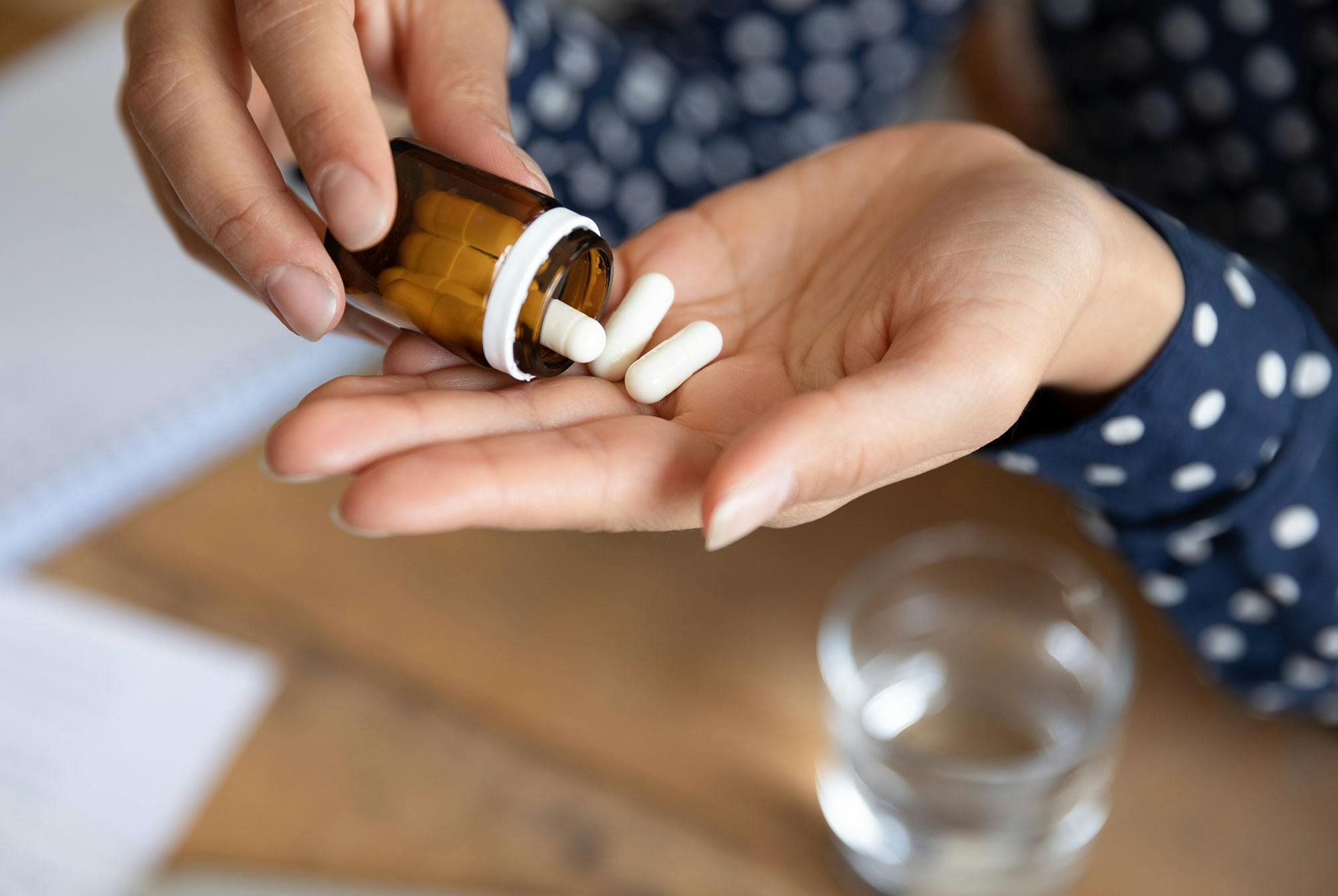 En kvinna häller smärtstillande tabletter från en medicinflaska i sin handflata.