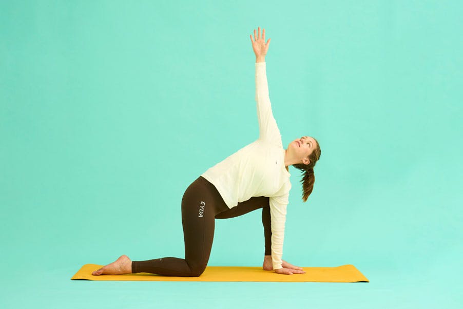 Kvinde laver knæstående rotation af ryggen.