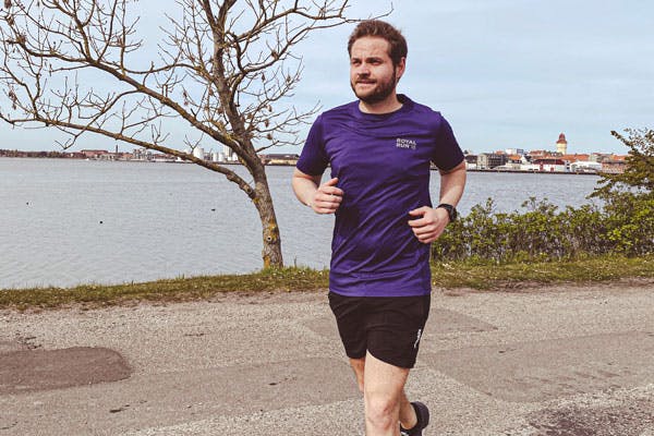 Mies juoksee veden äärellä