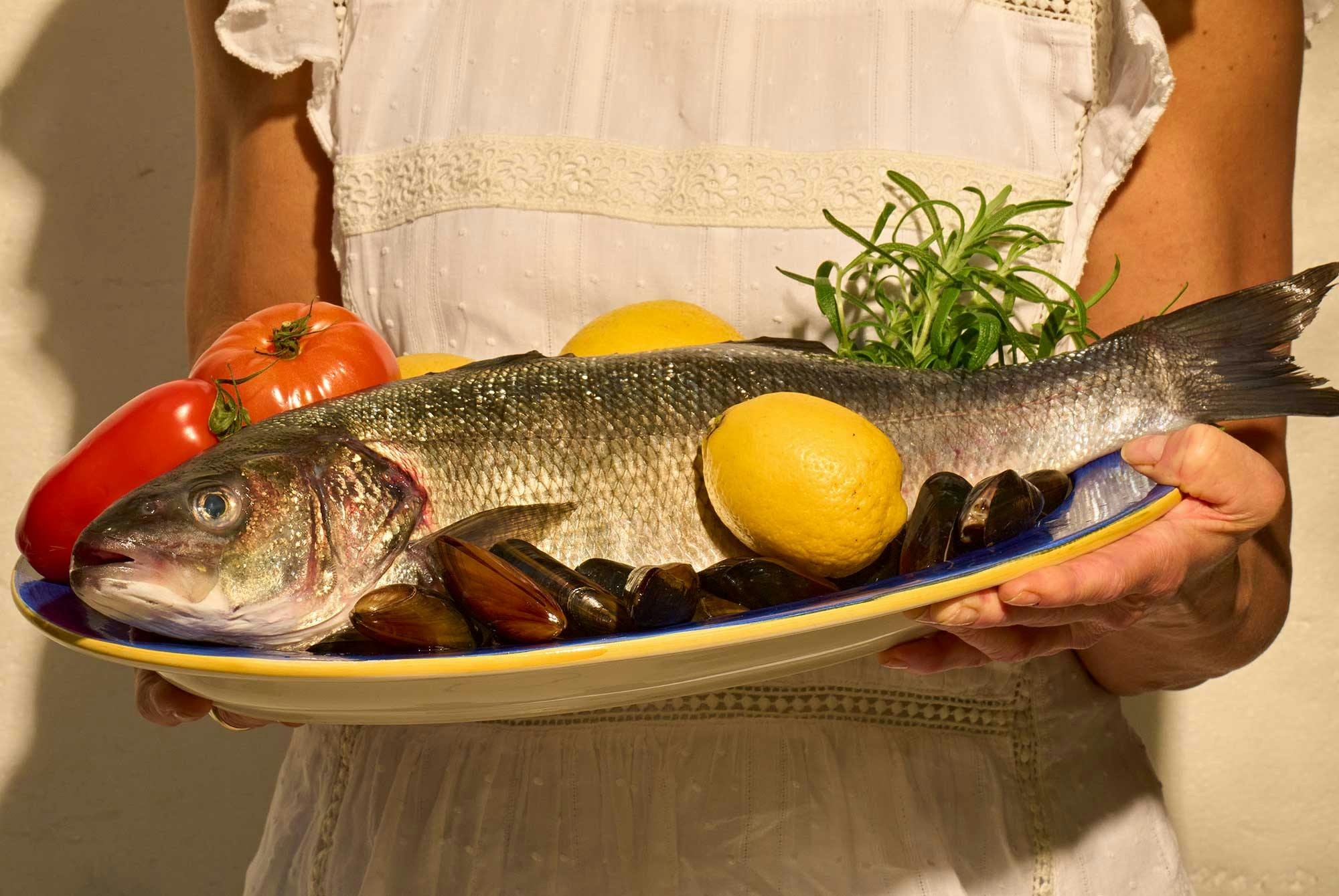 Kvinde står med et fad med en hel laks, klar til at lave mad med omega-3 fedtsyre.