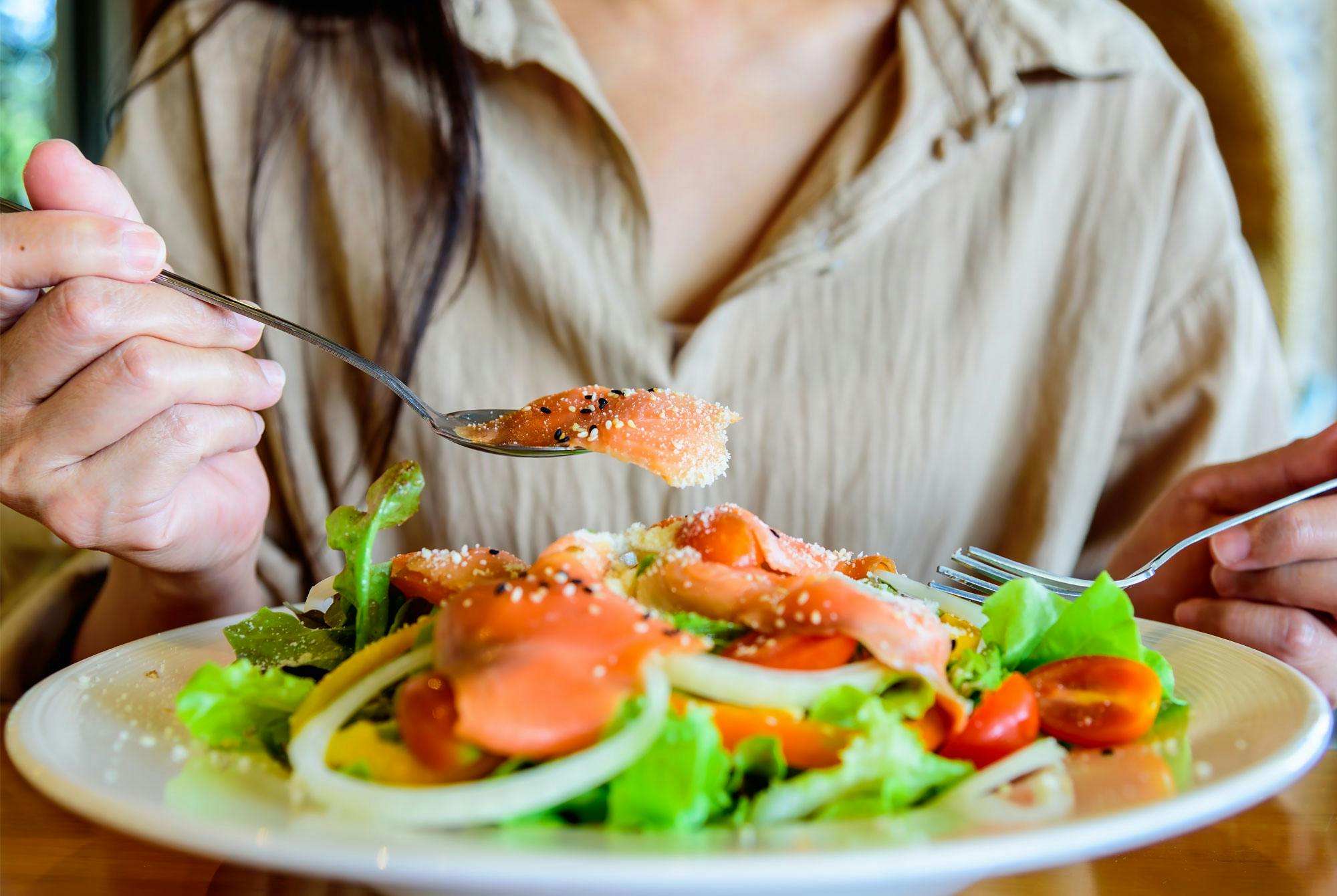 Nainen syö kalaa sisältävää ruokaa