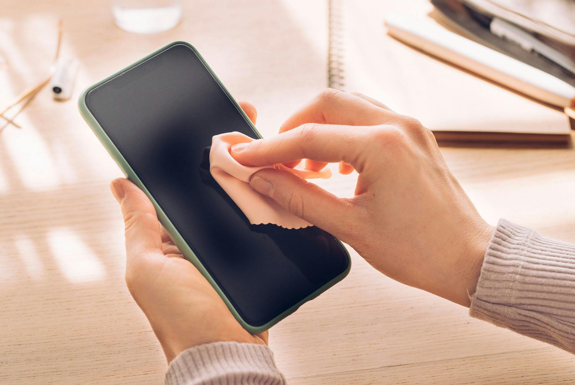 Kvinde renser sin mobiltelefon for bakterier.