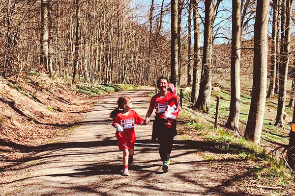 Nainen ja lapsi kävelevät soratiellä maaseudulla