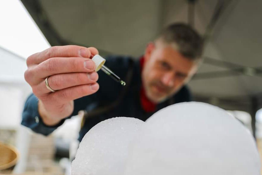 Gusmester, der putter æteriske olier på iskugler inden saunagus