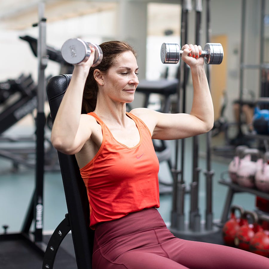 Kvinne gjør skulderpress med albuene vippet forover