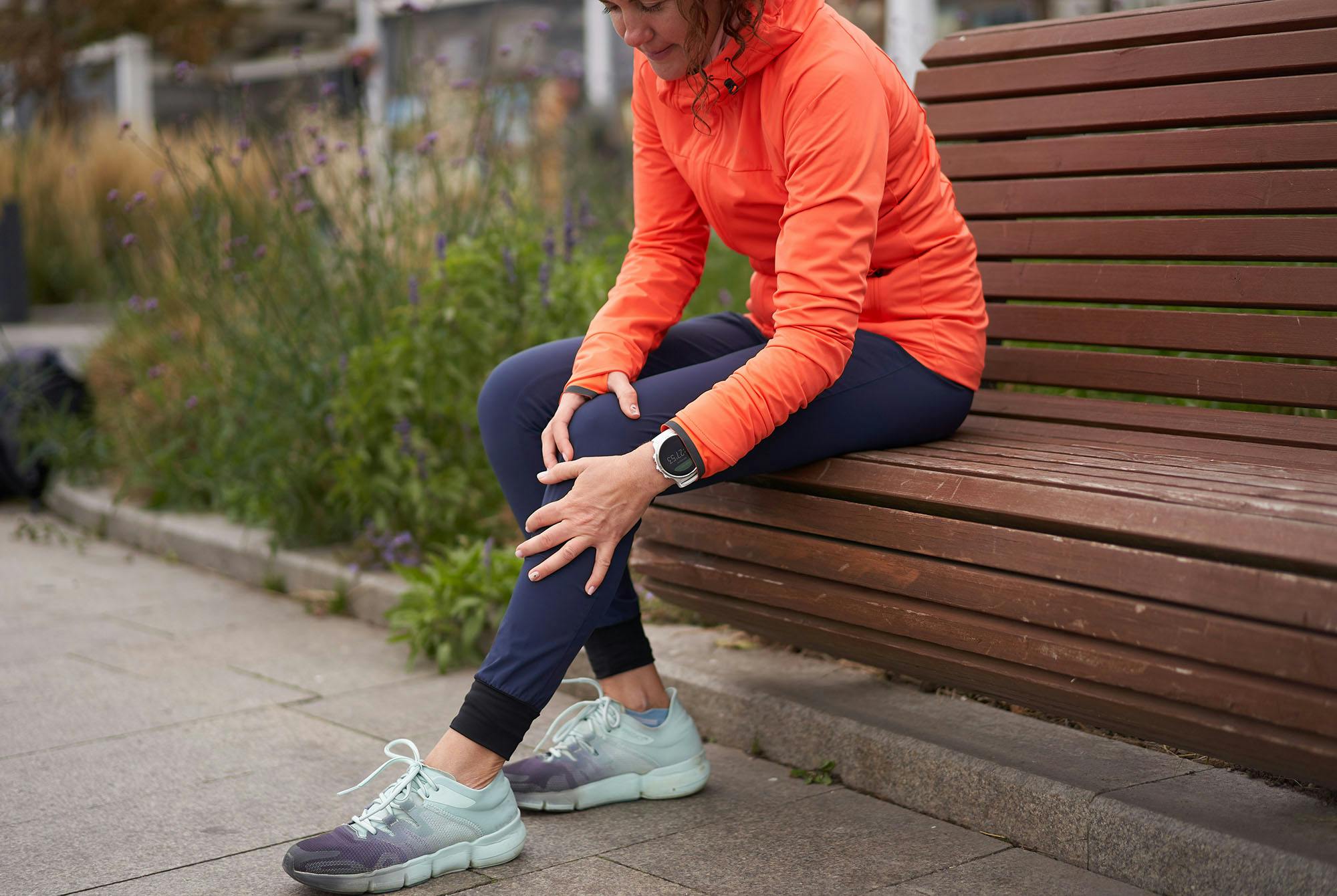 kvinde i løbetøj, der tager sig til knæet.