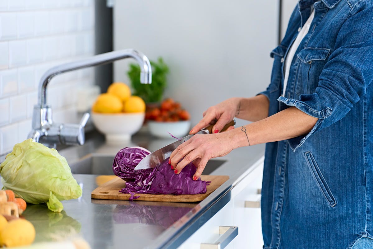 Hænder, der snitter kål, spidskål i et køkken