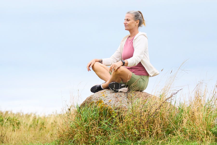 Nainen meditoi kivellä istuen