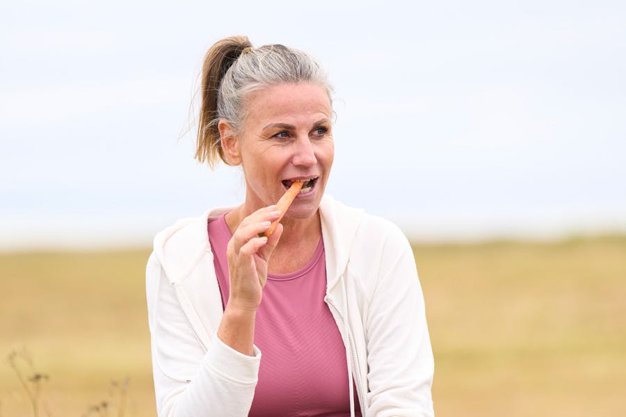 Nainen syö porkkanaa ulkona