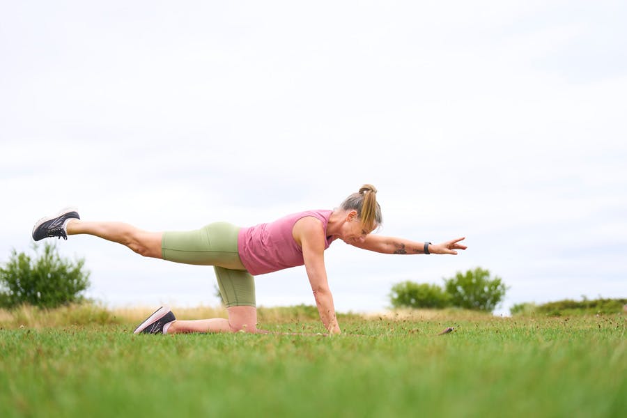 Nainen tekee lihastreeniä nurmikolla