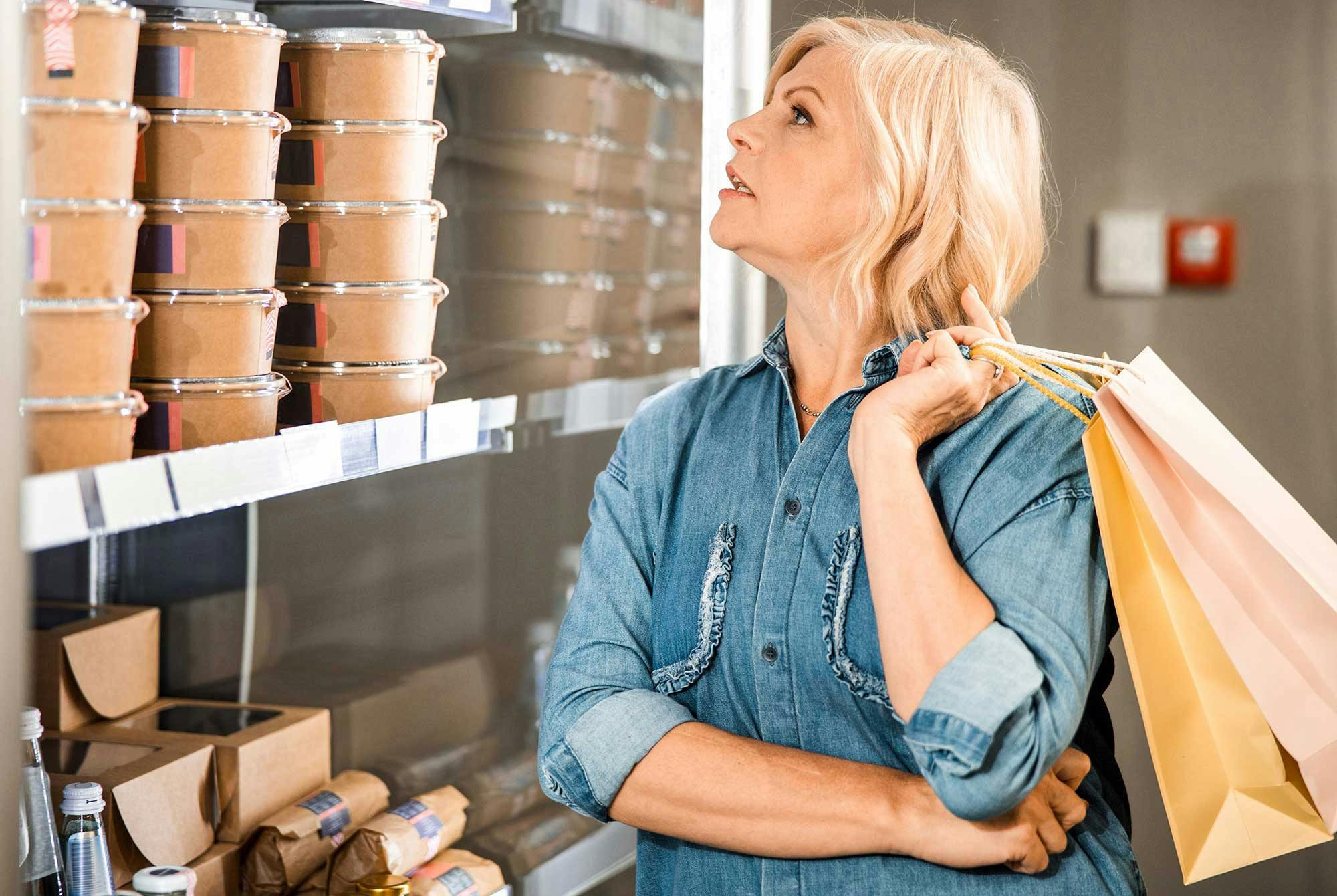 En kvinna står i en stormarknad och funderar på vad hon ska köpa.