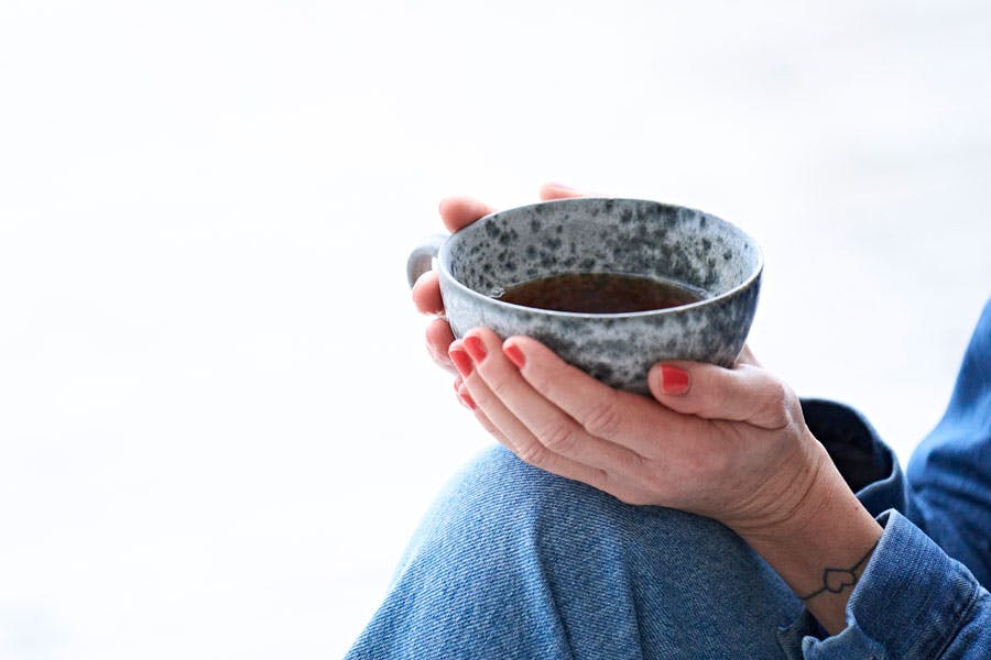 Nærbillede af hænder, der holder en kop te