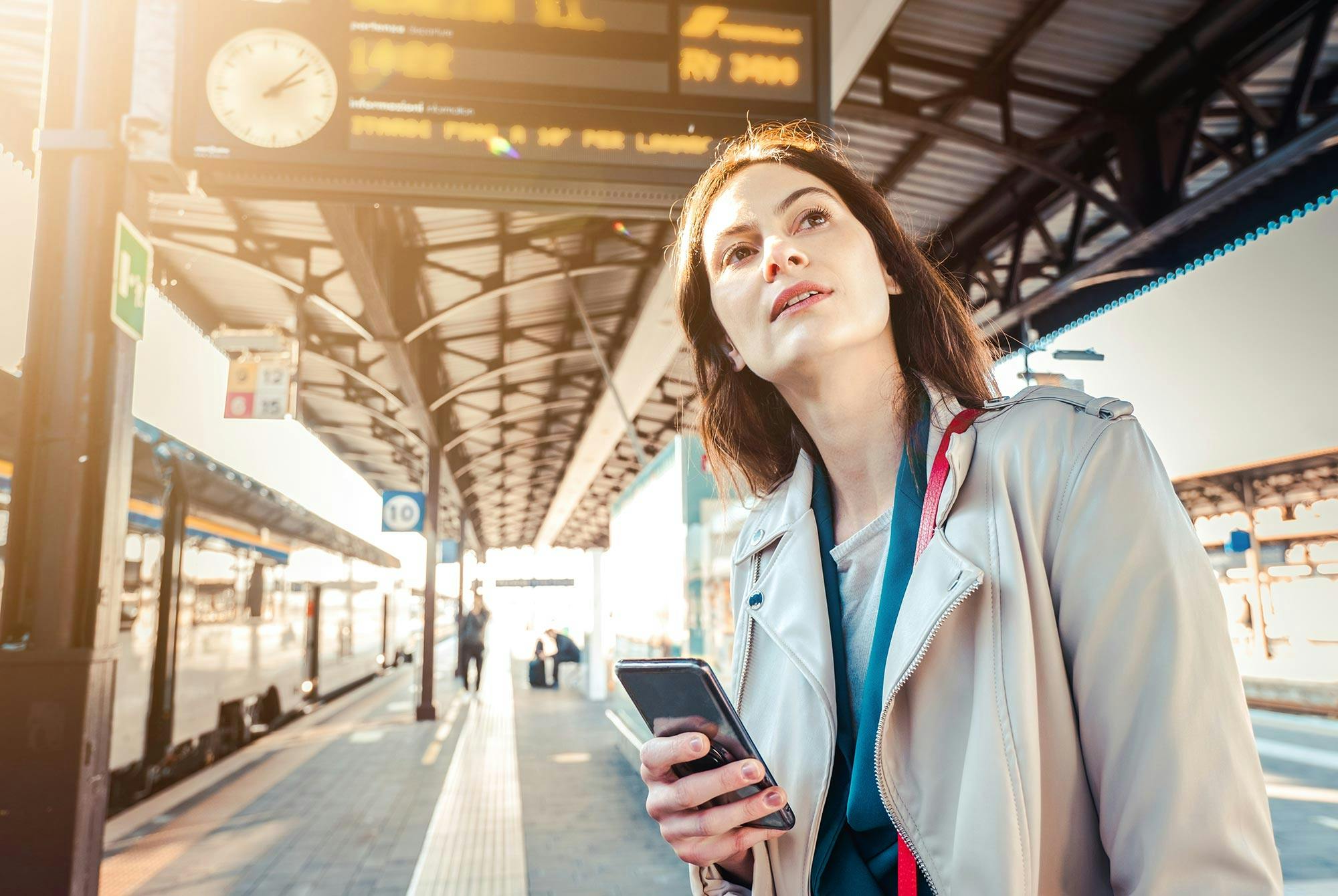 En kvinne står og venter på et fly, mens hun ser på telefonen. Hun er tidspessimist.