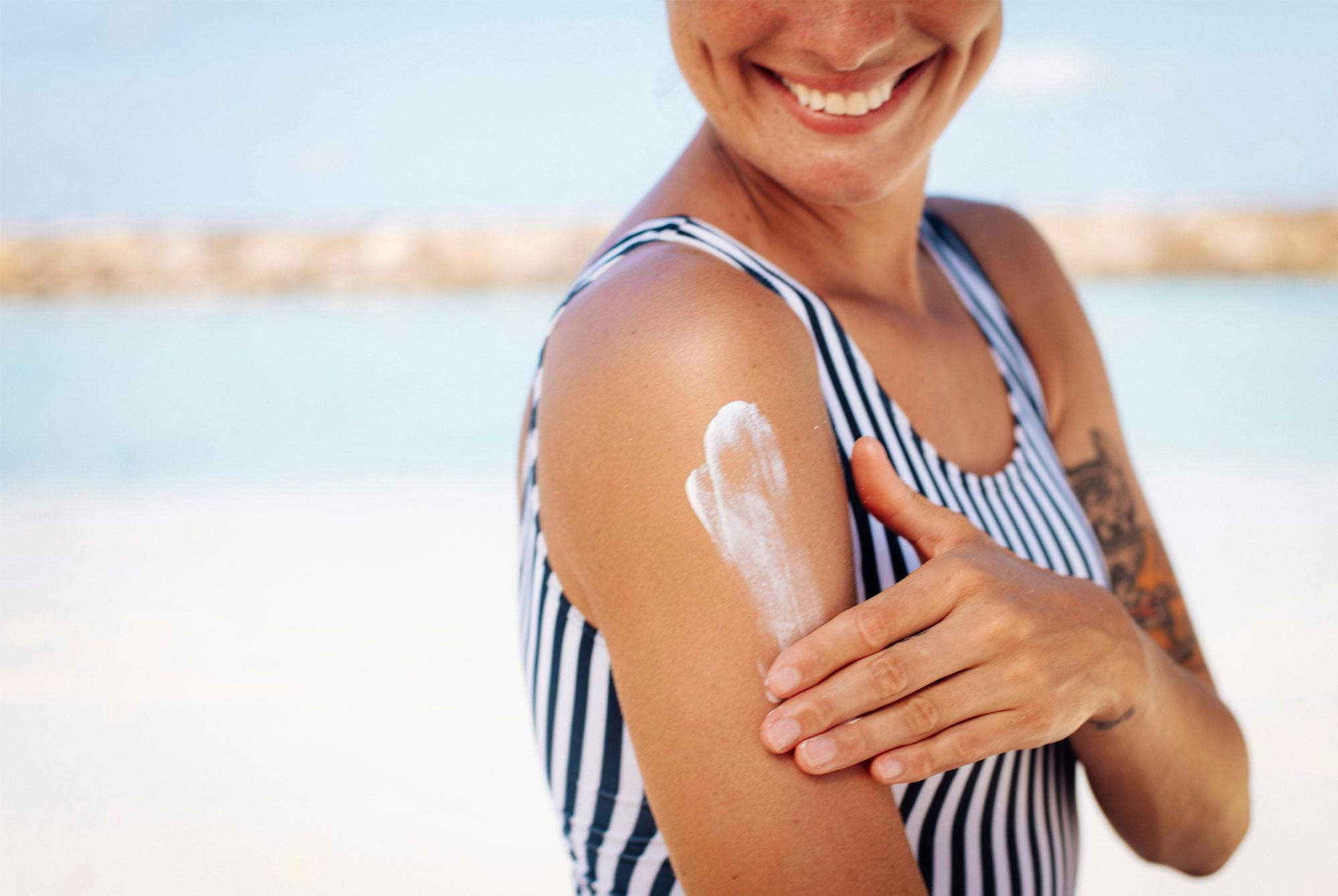 Kvinde i solen med højt UV-indeks smører sig med solcreme.