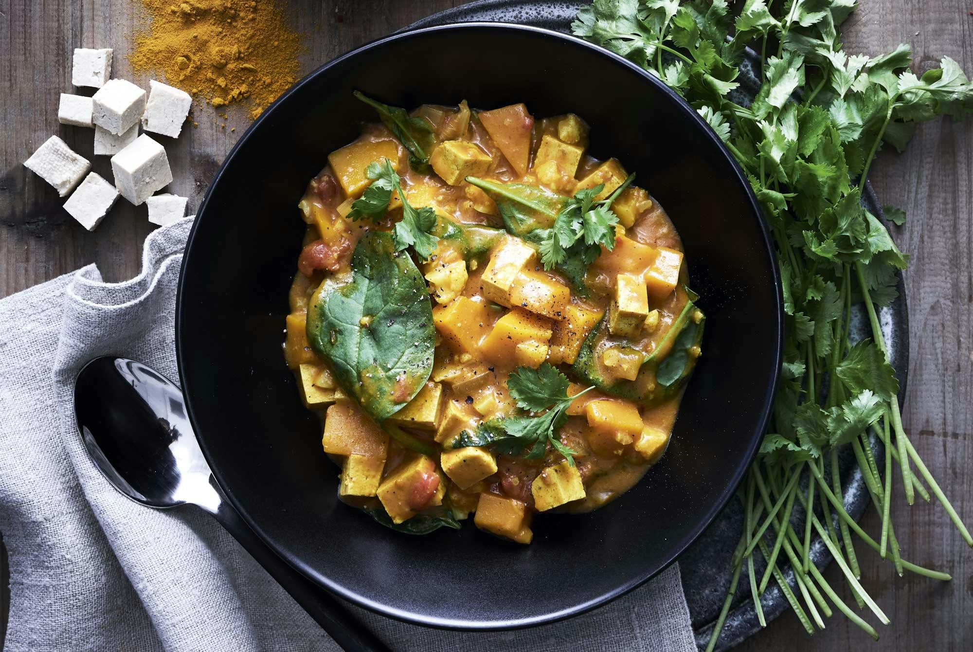 En skål med en krämig curry med grönt på toppen.