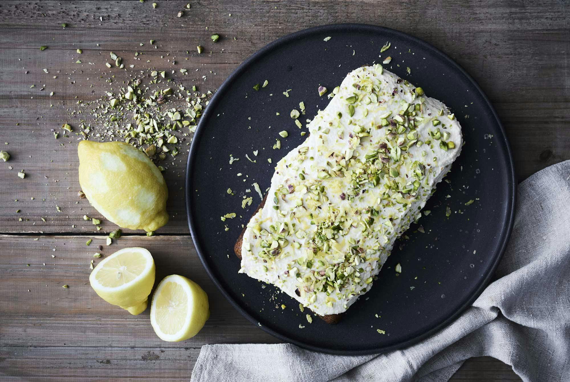 En kake med hvit frosting og pistasjenøtter drysset på toppen.