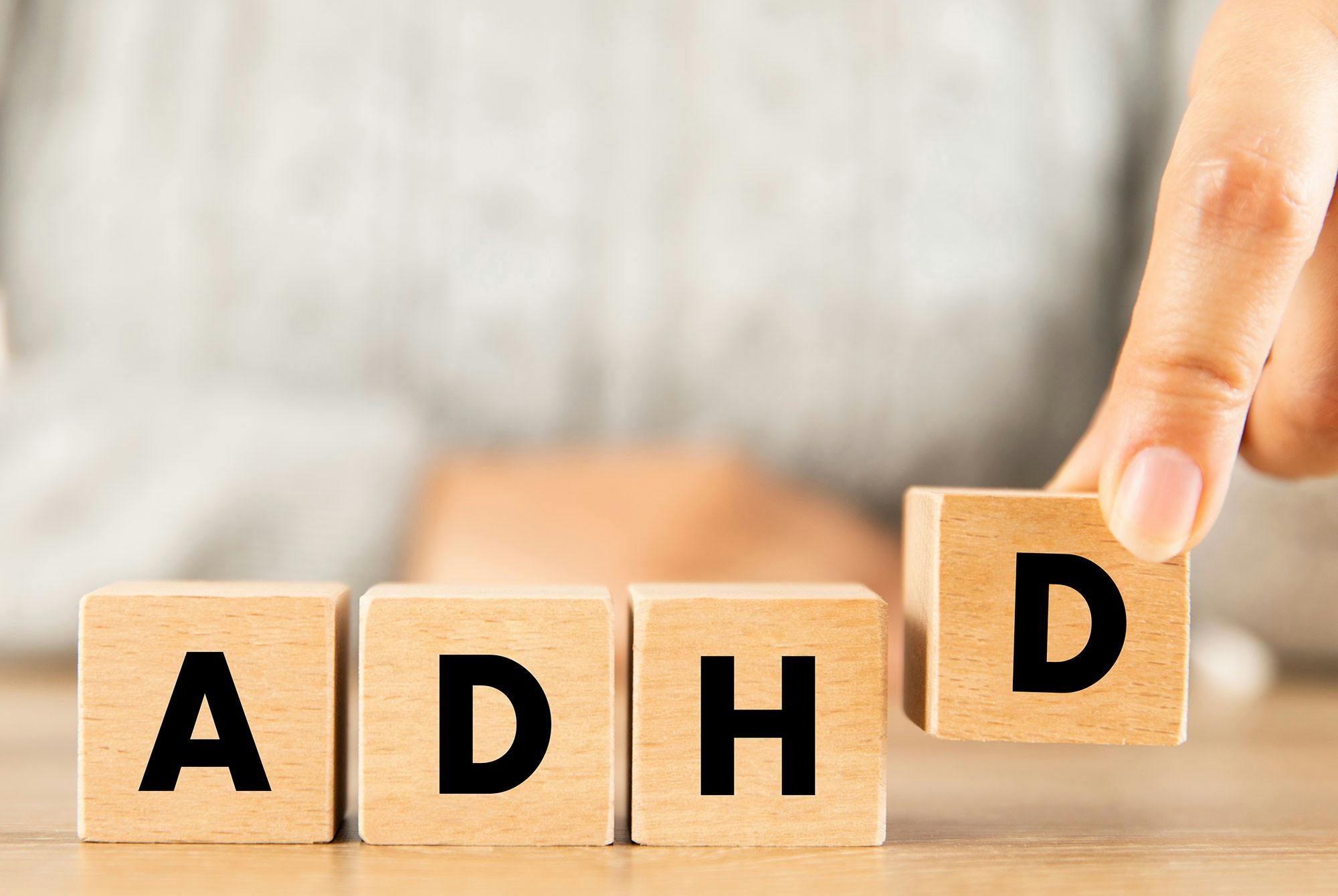 Kvinde med procrastination lægger fire bogstaver "ADHD" op på stribe.