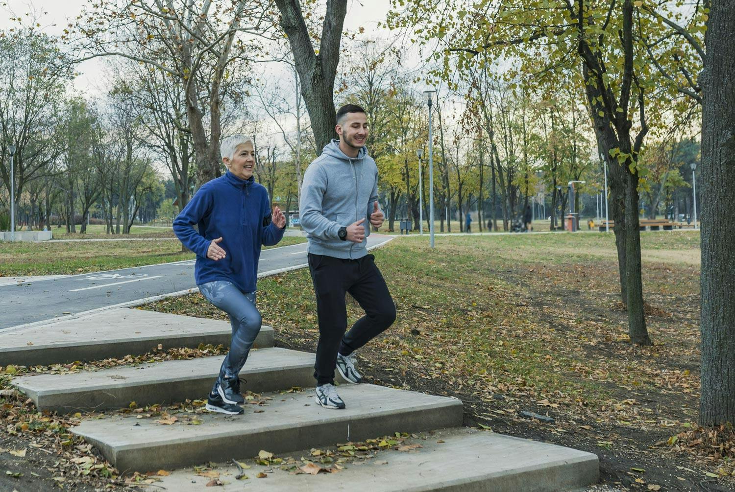Eldre kvinne og ung mann – mor og sønn – løper sammen og forbrenner kalorier.