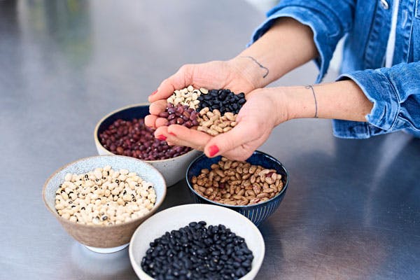 En handfull och flera små skålar med baljväxter