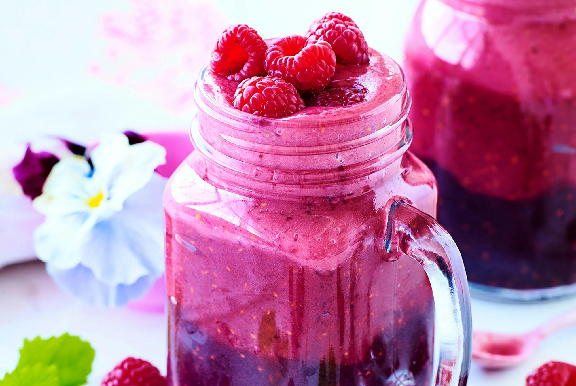 Glas med pink drik, pyntet med bær og blomster