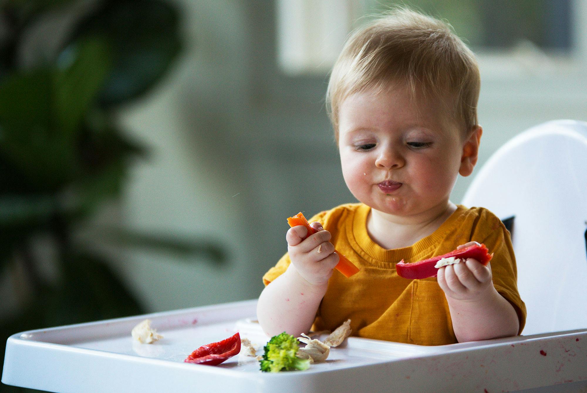 Baby spiser grønnsaker med stor glede.