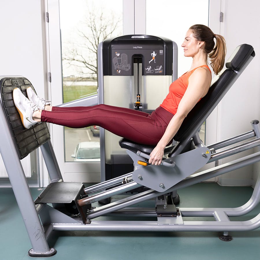 Nainen tekee harjoitetta jalkaprässi / leg press