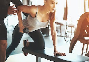 Kvinne tar foroverbøyd roing på treningsbenk