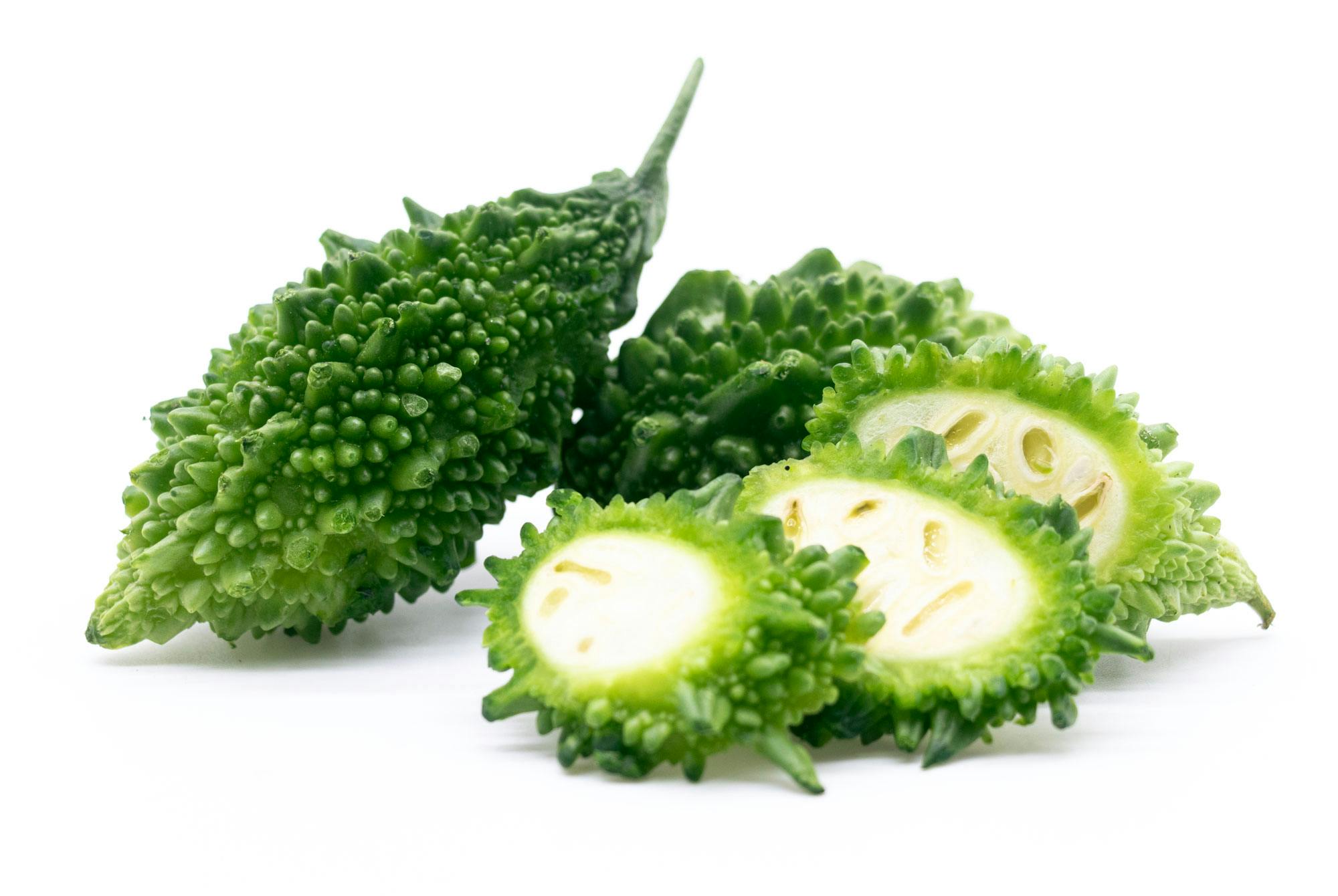 Bitter melon hel och skivad på en vit bakgrund