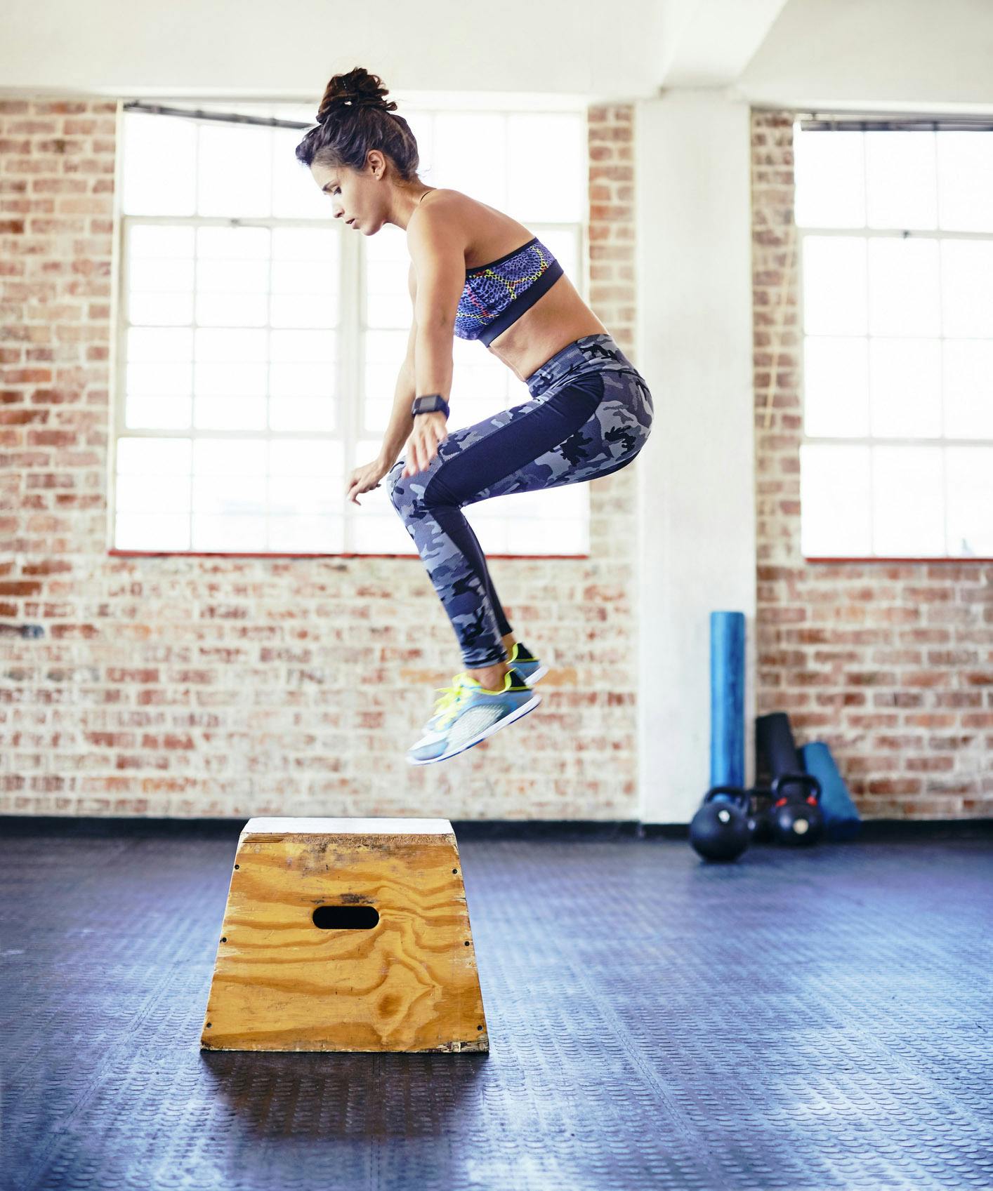 Kvinde laver box jumps på trækasse i fitnesscenter