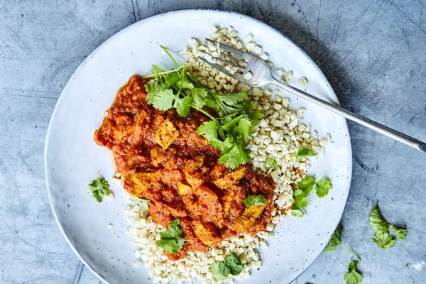en tallrik med chicken tikka masala och blomkålsris